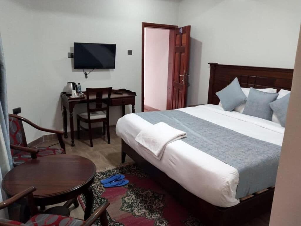 A bedroom with a bed, a desk, a chair, and a television.