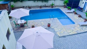 Ein Pool mit einer Steinterrasse, umgeben von Blumentöpfen und Gartenmöbeln.