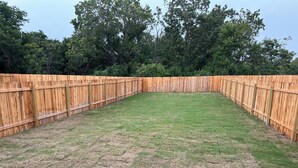A fenced backyard with a grassy lawn and trees in the background. - Charming 3-bedroom home with WiFi, King bed in fabulous Copperas Cove (Copperas Cove)
