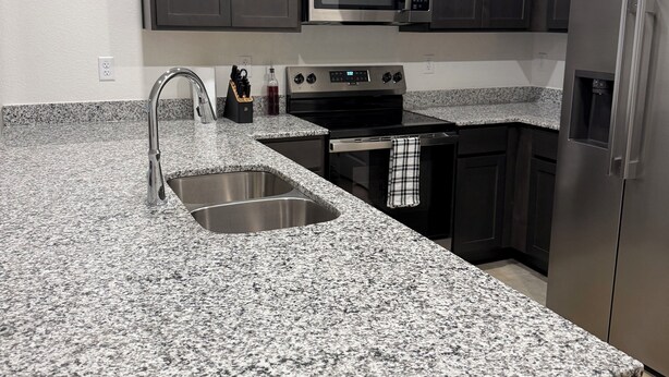 A kitchen with granite countertops, stainless steel appliances, and dark cabinetry. - Charming 3-bedroom home with WiFi, King bed in fabulous Copperas Cove (Copperas Cove)