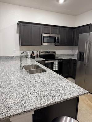 A kitchen with granite countertops, stainless steel appliances, and dark cabinetry. - Charming 3-bedroom home with WiFi, King bed in fabulous Copperas Cove (Copperas Cove)