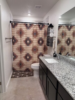 A bathroom with a shower curtain, toilet, sink, and mirror. - Charming 3-bedroom home with WiFi, King bed in fabulous Copperas Cove (Copperas Cove)