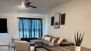 A living room with a sectional sofa, a dining table with benches, a ceiling fan, and a potted plant. - Charming 3-bedroom home with WiFi, King bed in fabulous Copperas Cove (Copperas Cove)