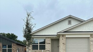 A two-story house with a garage, a front yard with a small tree, and a brick facade. - Charming 3-bedroom home with WiFi, King bed in fabulous Copperas Cove (Copperas Cove)