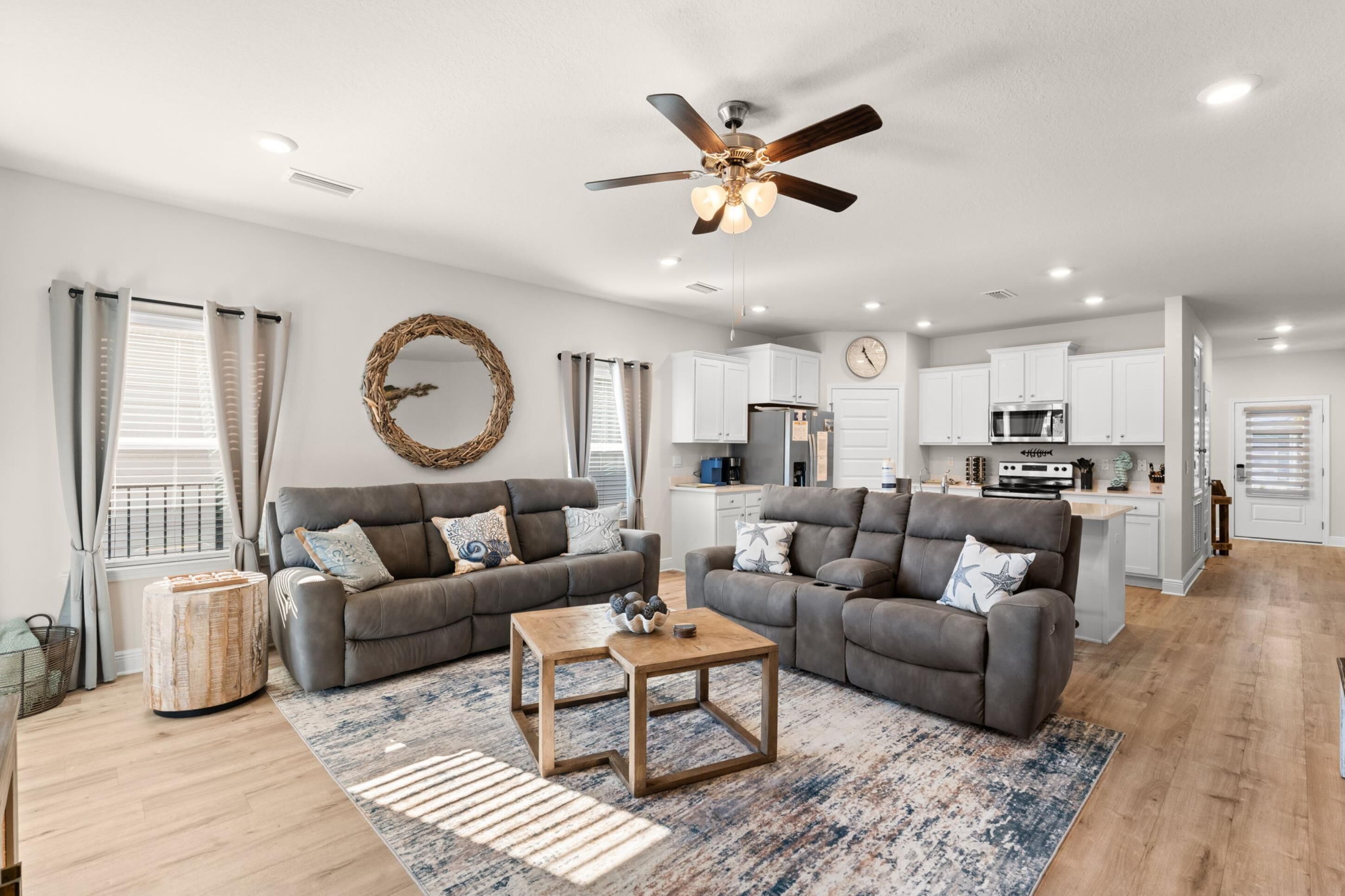 A modern living room with two grey sofas, a wooden coffee table, and a ceiling fan.
