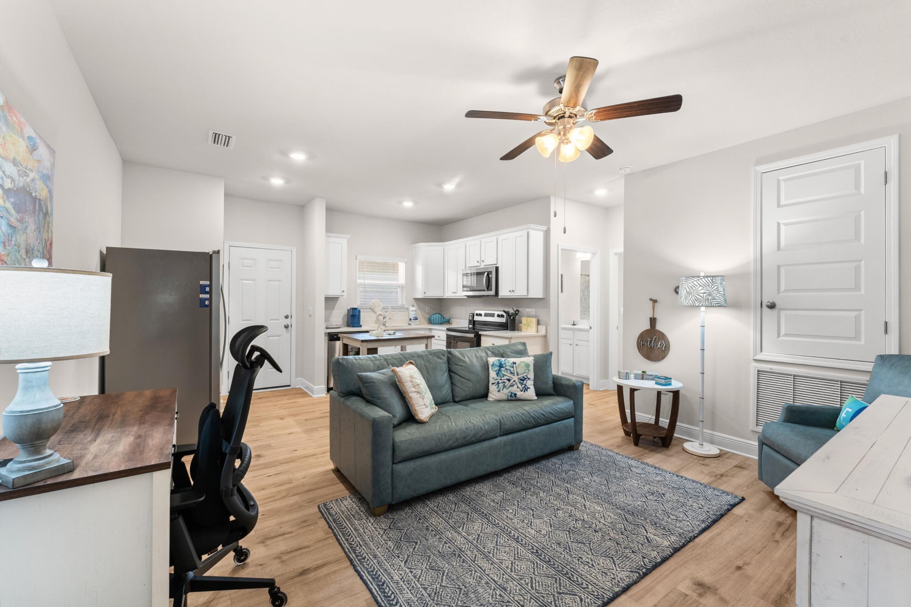 A modern living room with a grey sofa, a small coffee table, and a ceiling fan.