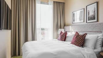 Una habitación de hotel con una cama grande, vista a la ciudad y dos cuadros en la pared.