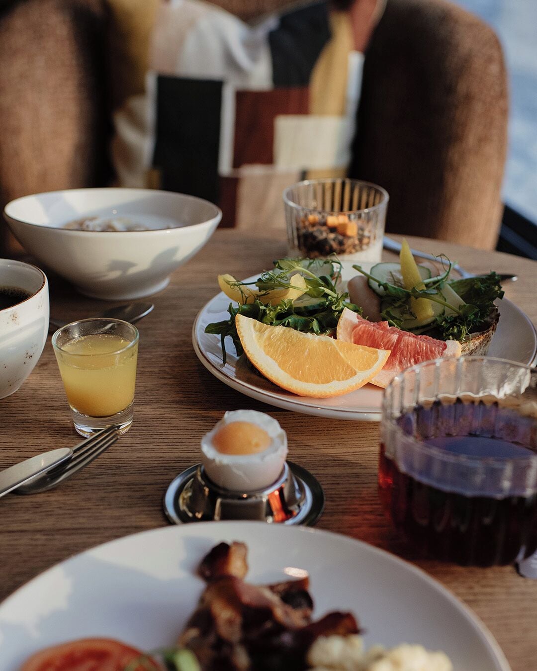 A dining table with a plate of food, a glass of juice, and a cup of tea.