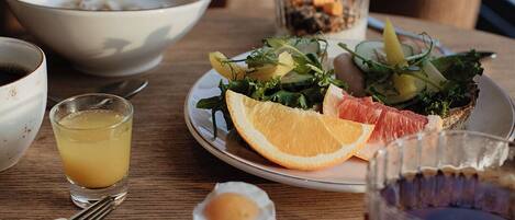 A dining table with a plate of food, a glass of juice, and a cup of tea.