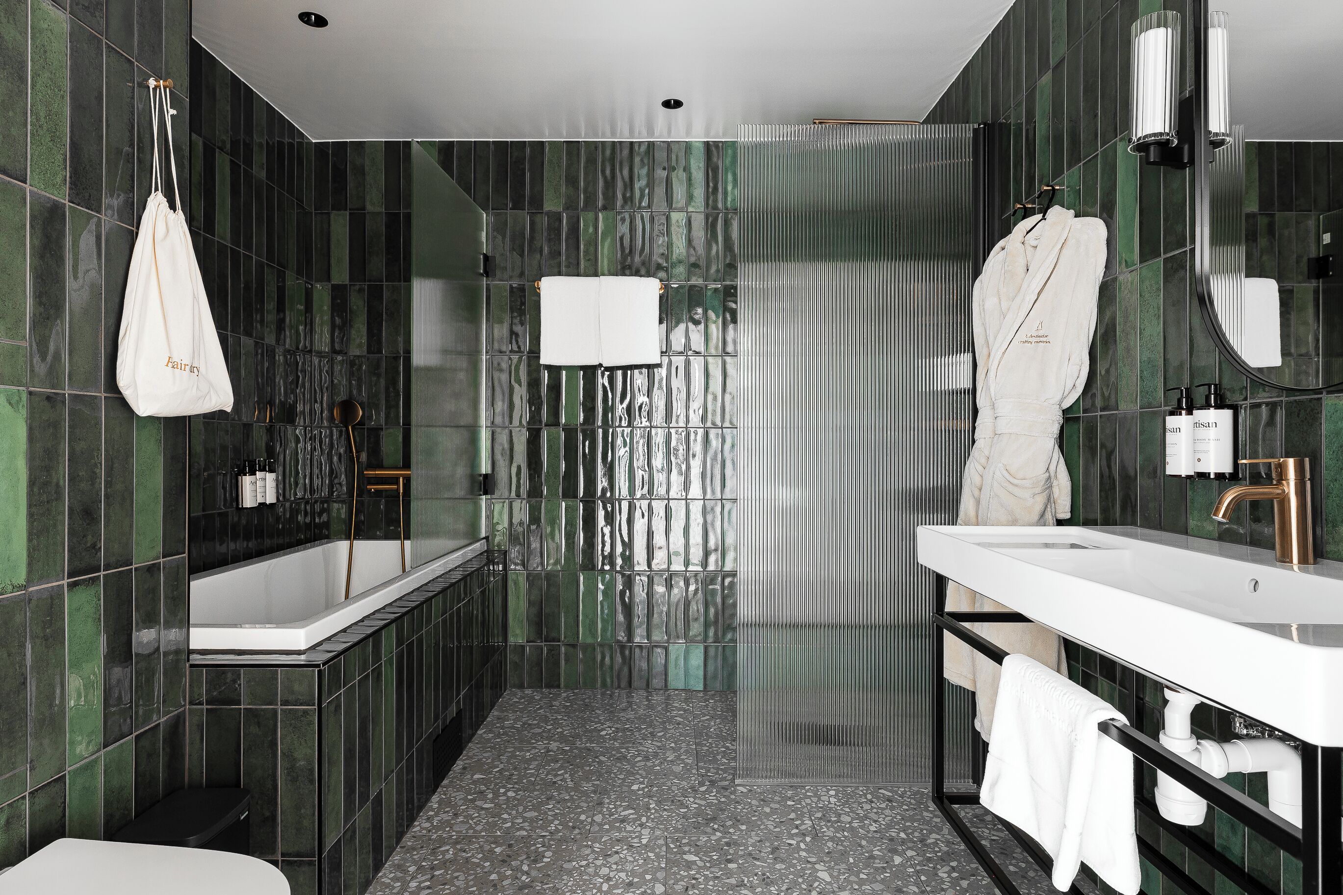 Un baño moderno con una bañera independiente, un espejo grande y un mueble de tocador con toallero.