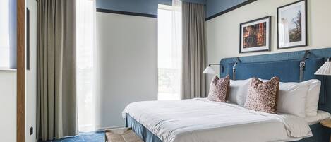 A hotel room with a large bed, a bench, and two framed pictures on the wall.