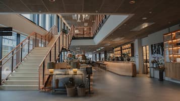 A spacious lobby with a staircase, seating area, and a bar.