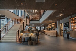 A spacious lobby with a staircase, seating area, and a bar. - Hernö Gin Hotell (Harnosand)