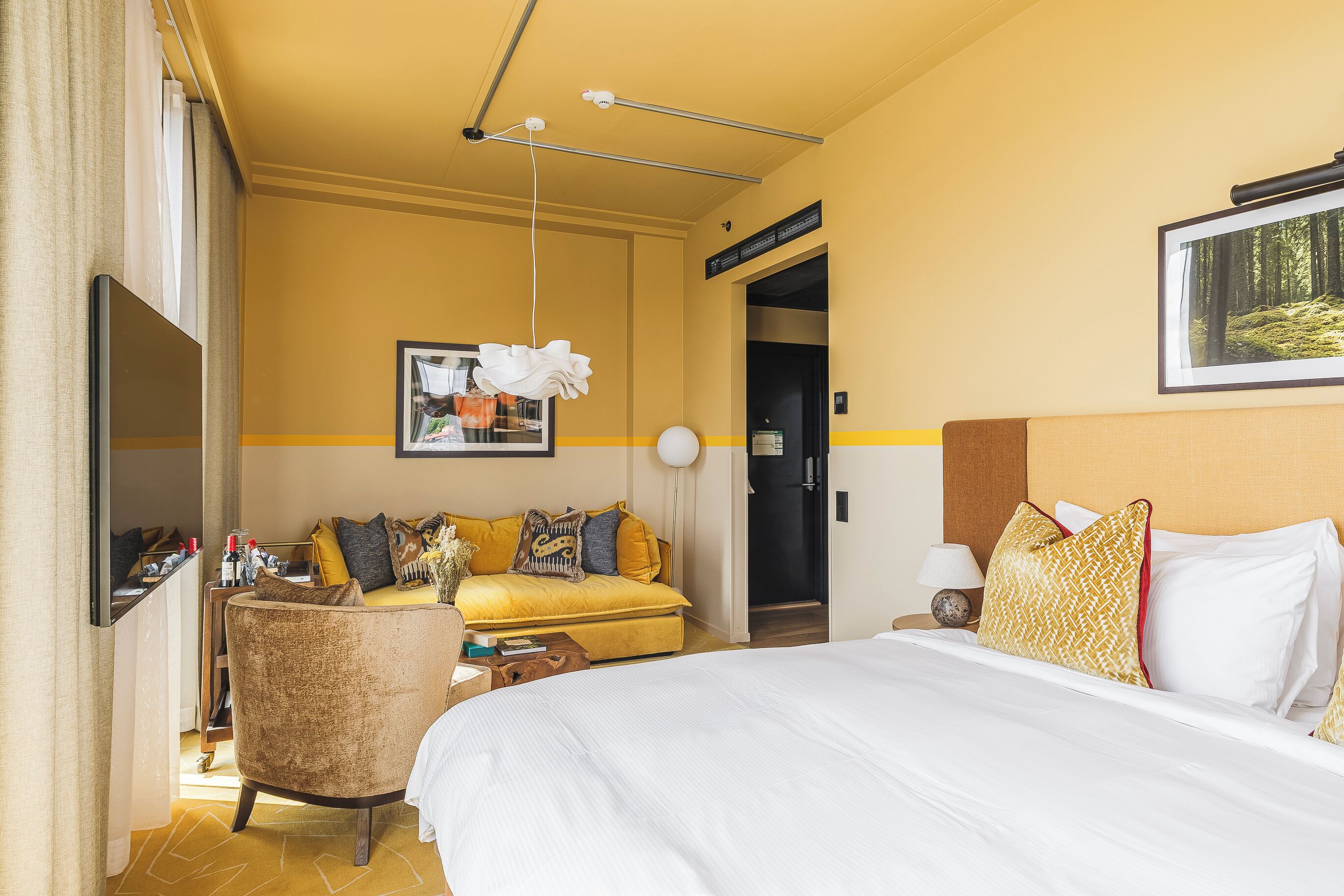 Een hotelkamer met een bed, een slaapbank, een bureau en een deur naar een badkamer.