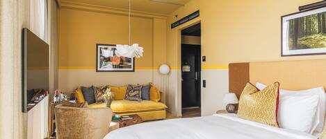 Una habitación de hotel con cama, sofá, escritorio y puerta que da a un baño.