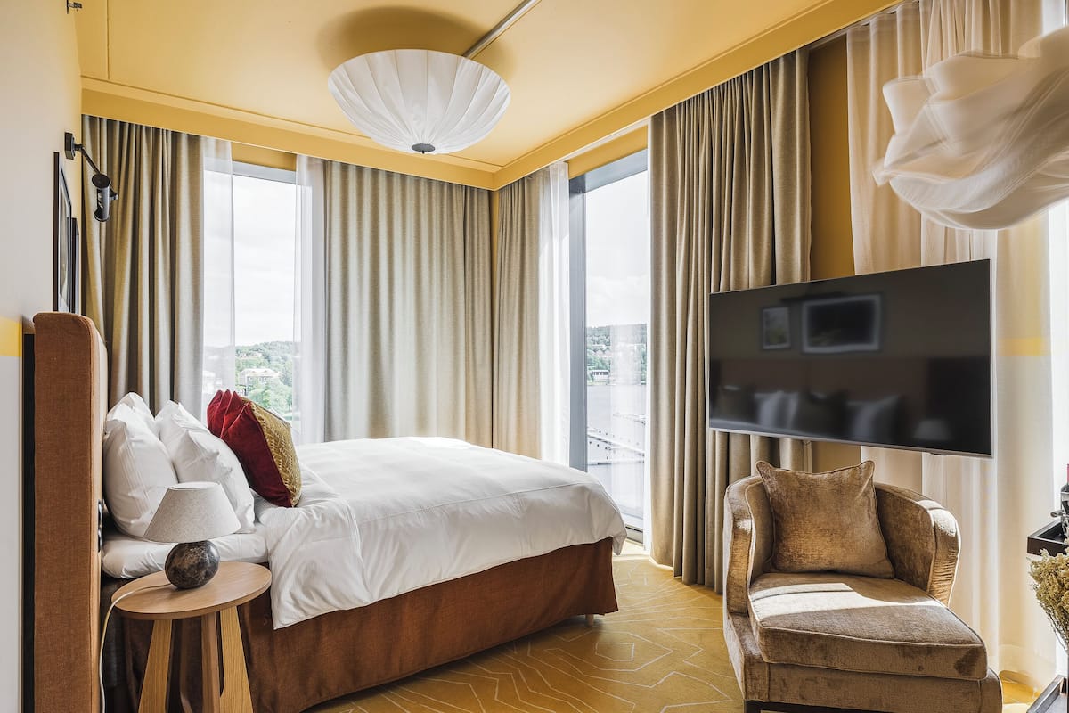 Une chambre d’hôtel avec un grand lit, une télévision, un canapé et une vue sur la ville.