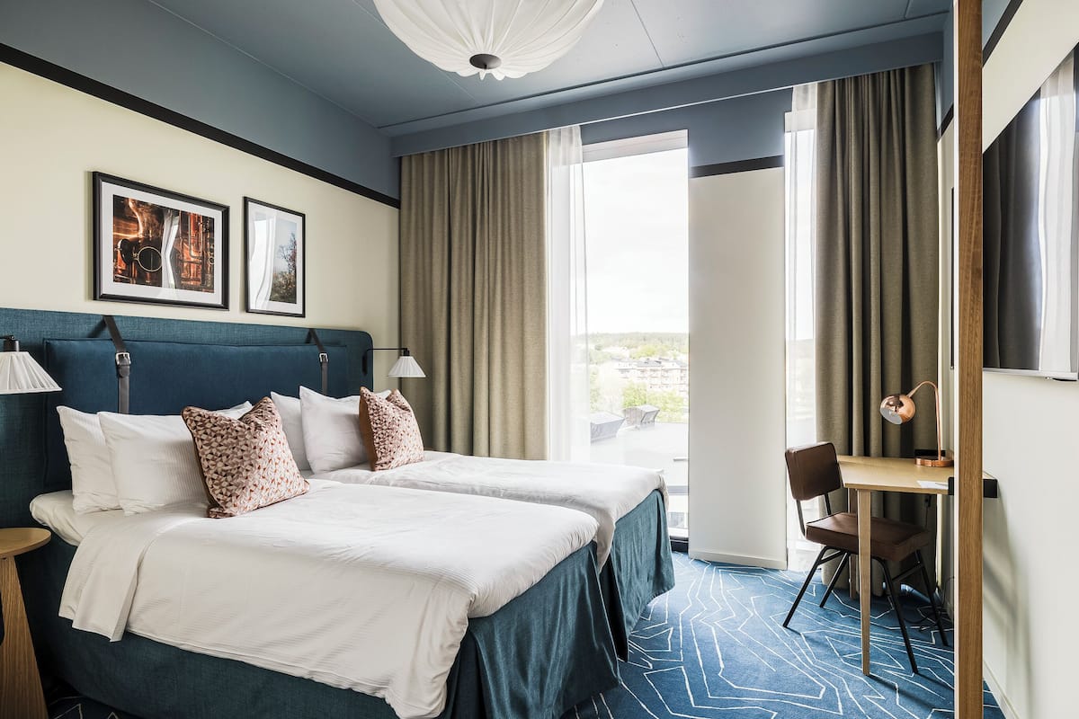 Une chambre d’hôtel avec deux lits, un bureau et une chaise.