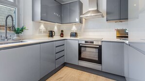 Une cuisine moderne avec des meubles gris, un four encastré et un évier.