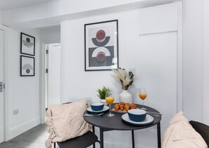 Enjoy meals in this stylish dining area with a round table, beige throw blanket, and abstract artworks.
