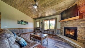 A cozy living room with a stone fireplace, leather sofa, and wooden flooring. - "Her Endless Views" cabin has incredible mountain views, hot tub, and firepit (Murphy)