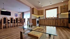 A modern kitchen with wooden cabinets, a built-in washing machine, and a glass dining table. - Holiday Home Wisniowa With Pool and Mountains (gmina Iwierzyce)