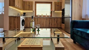 A modern kitchen with wooden cabinets, a glass dining table, and a blue sofa. - Holiday Home Wisniowa With Pool and Mountains (gmina Iwierzyce)