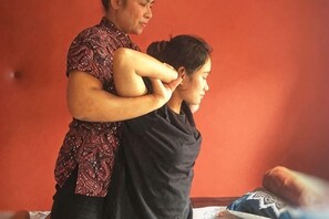 A person performing a massage on another individual in a room with a plain wall. - Anggun Lodge Private Room with Sharing Bathroom (Semporna)