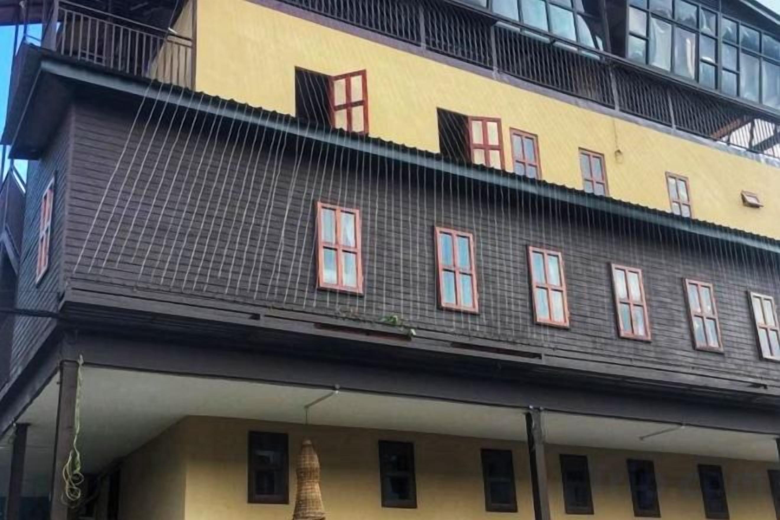 A multi-story building with a yellow facade and multiple windows.