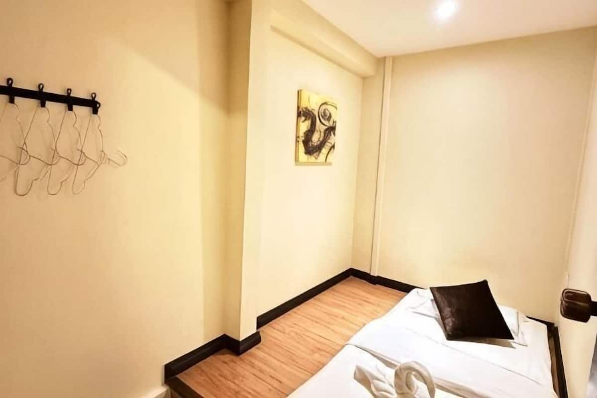A hotel room with a bed, a wall-mounted coat rack, and a framed artwork.
