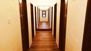 A long, narrow hallway with wooden flooring and doors on both sides. - Anggun Lodge Private Room with Sharing Bathroom (Semporna)