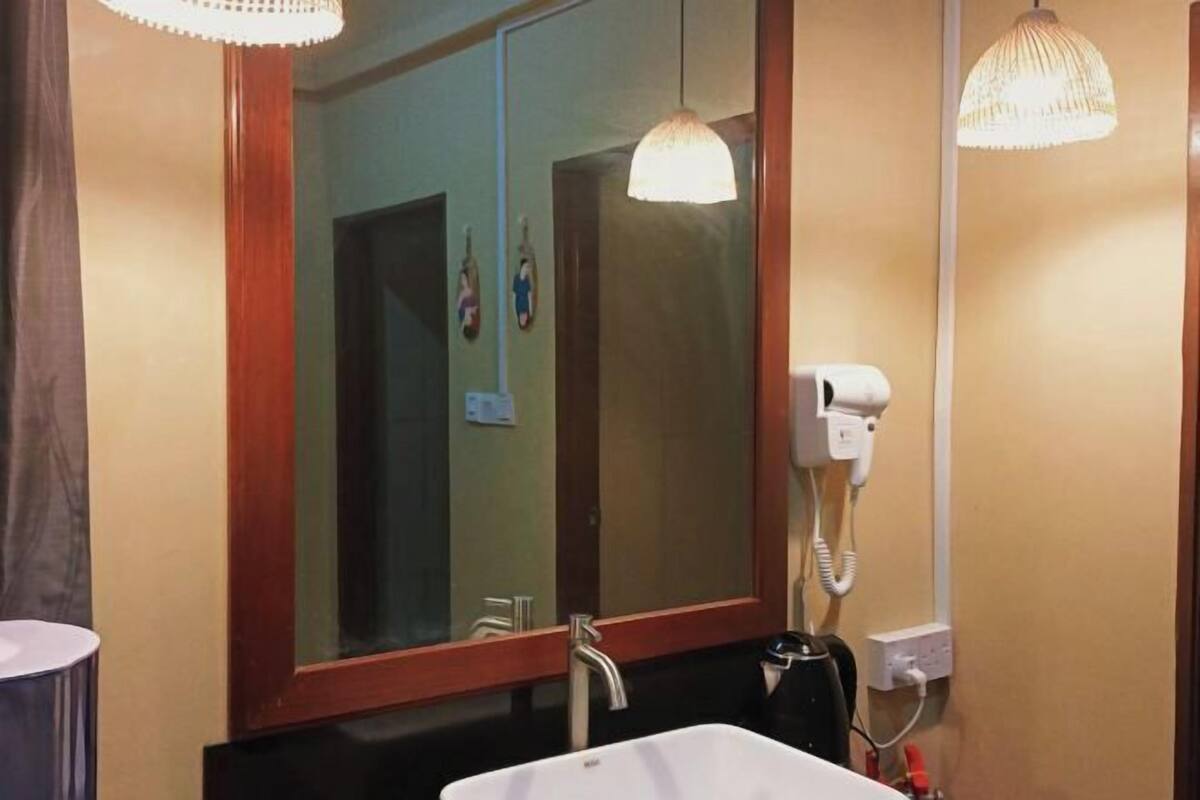 A bathroom with a large mirror, a sink, a hairdryer, and a telephone.
