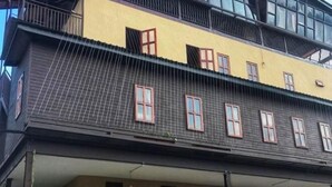 A multi-story building with a yellow facade and dark grey roof. - Anggun Lodge Private Room with Sharing Bathroom (Semporna)
