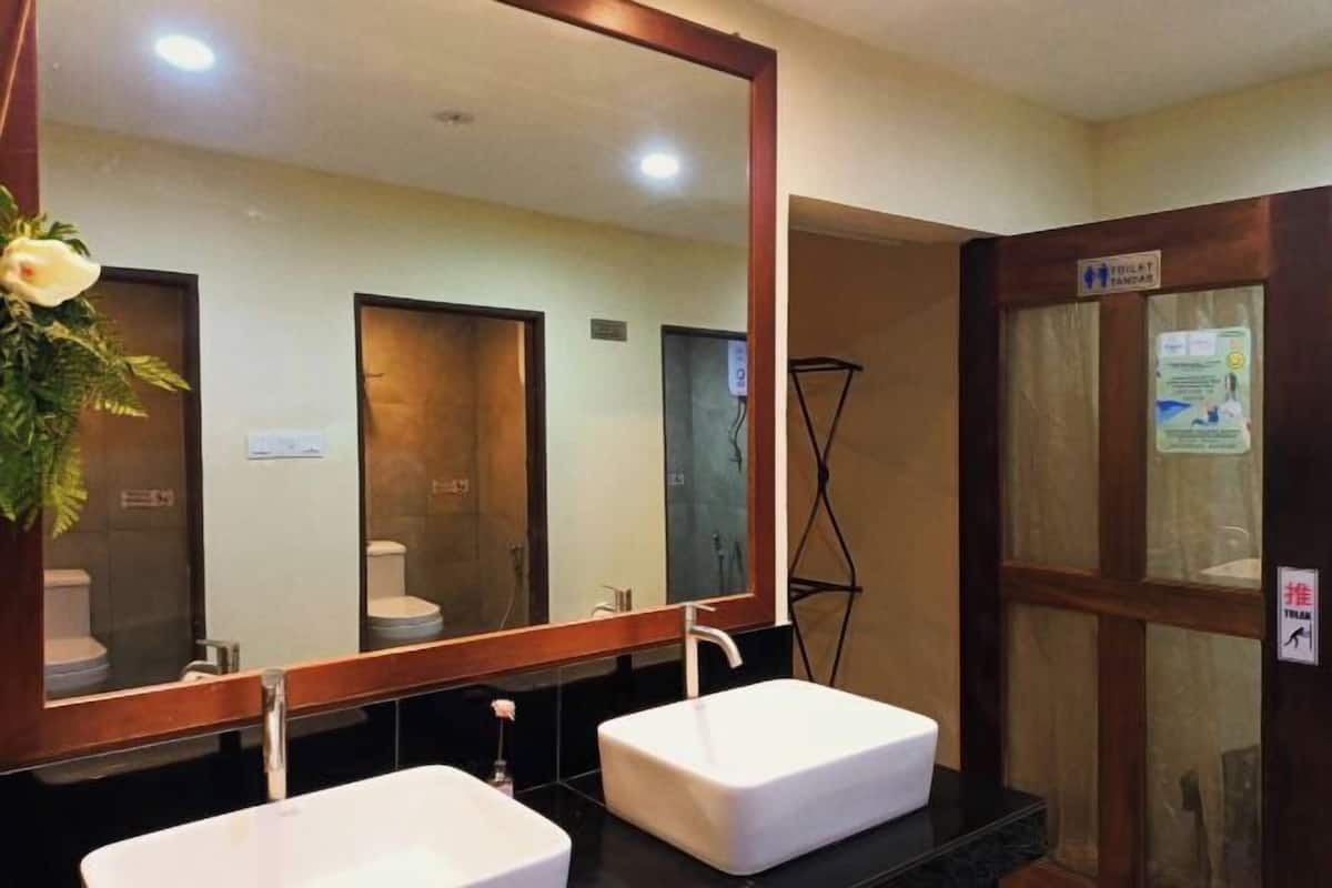 A bathroom with two sinks, a large mirror, and a shower area.