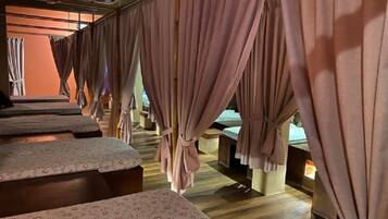 A room with multiple beds, each with a wooden headboard and a floral-patterned bedspread.