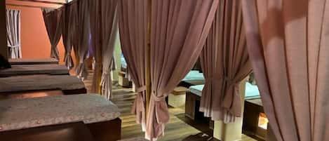 Una habitación con varias camas, cada una con cabecero de madera y colcha estampada con motivos florales.