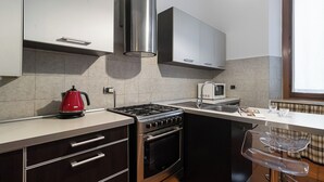 Une cuisine moderne équipée d’une cuisinière à gaz, d’un four et d’un four à micro-ondes. On y trouve également des placards, une bouilloire et un évier.