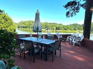 Eine Terrass mit Tisch und Stühlen mit Blick auf einen See und ein bewaldetes Ufer.