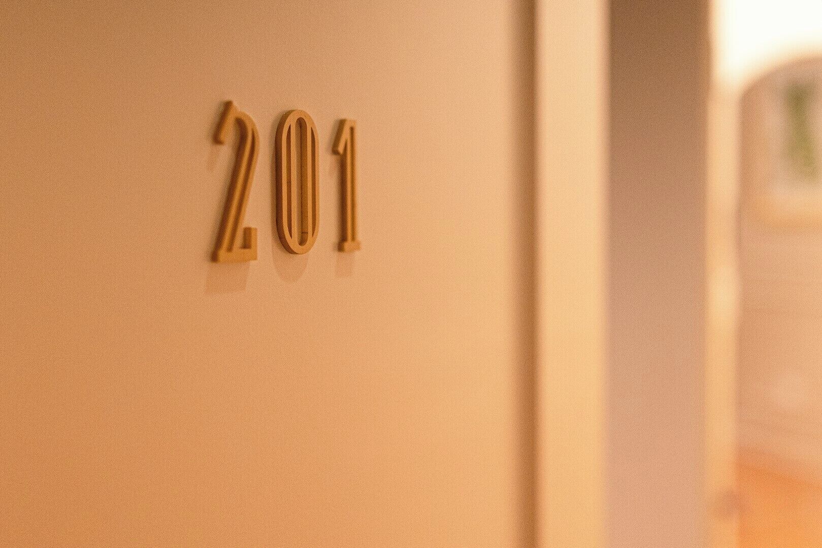 A close-up of a wall with the numbers "201" in a metallic finish.