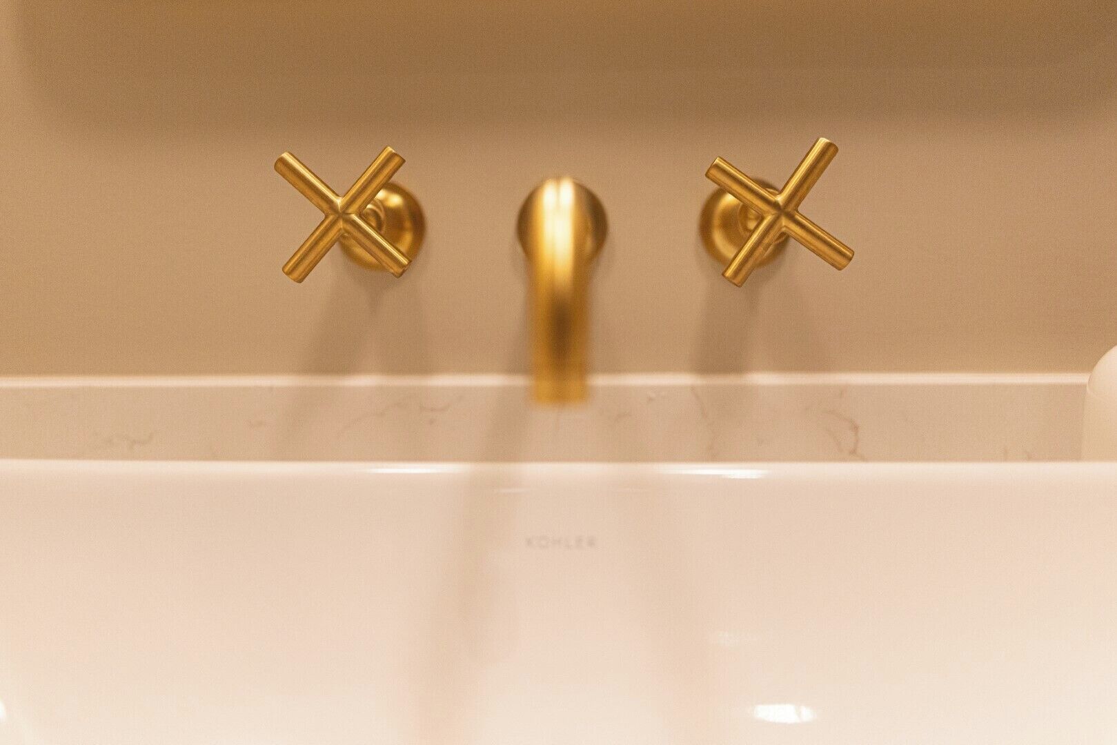 Una bañera con dos grifos dorados y un caño central.