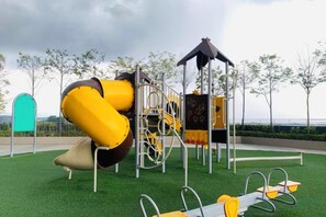 Un parque infantil con tobogán, estructuras de escalada y columpios.