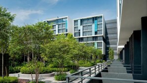 A modern building with a covered walkway, surrounded by greenery and trees. - CoreSoho Suite by BKAstaycation KotaWarisan Sepang KLIA Airport, Free Wifi (Sepang)