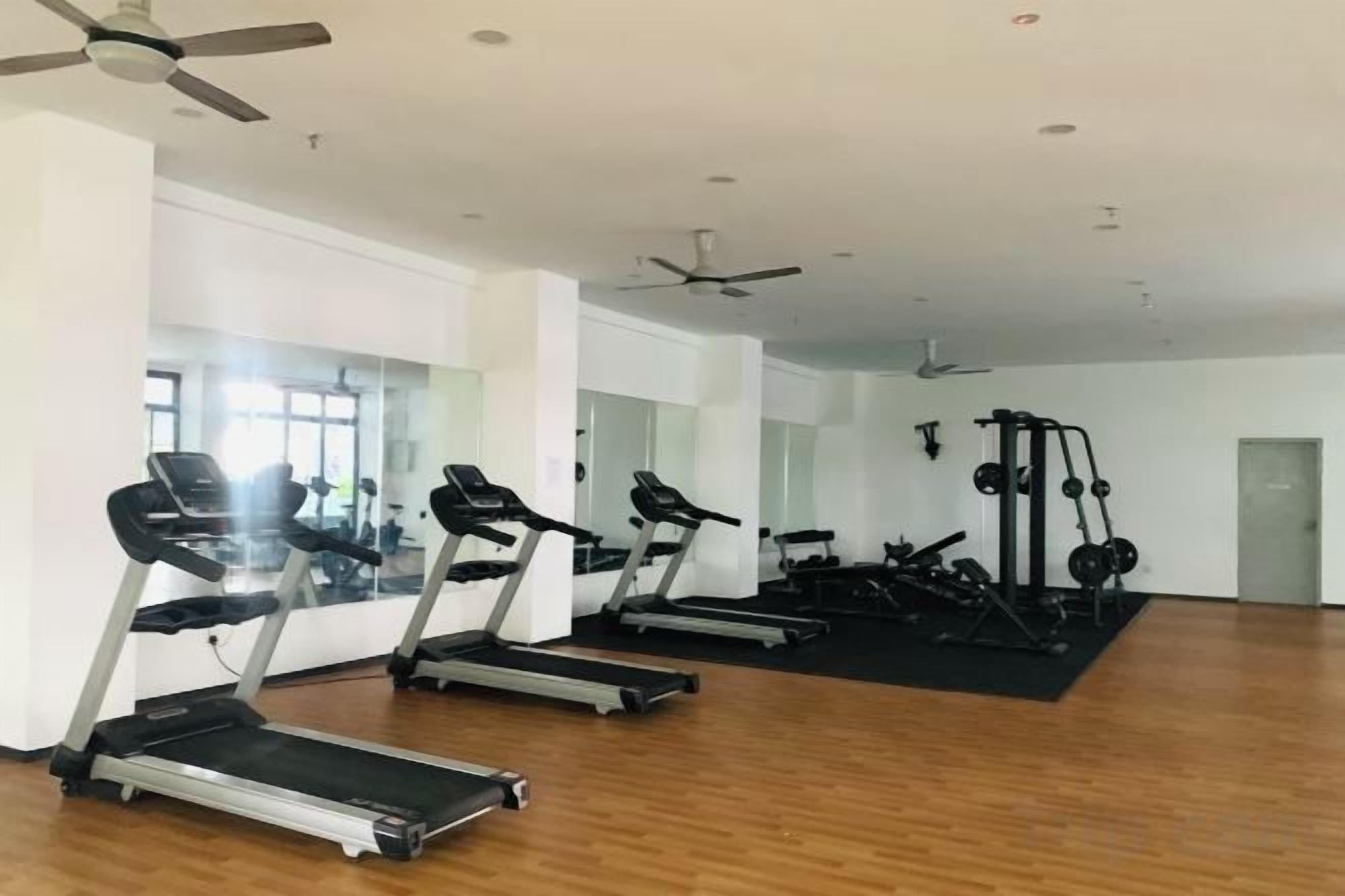 A gym with treadmills, a weight machine, and a mirror wall.