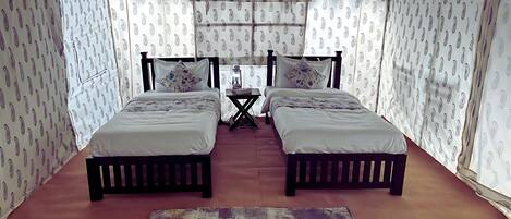 Una habitación con dos camas, una mesita y cortinas estampadas.