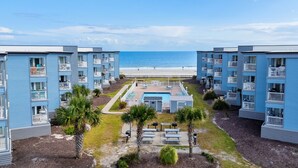 Un hotel sulla spiaggia con diversi edifici blu, una piscina e palme.