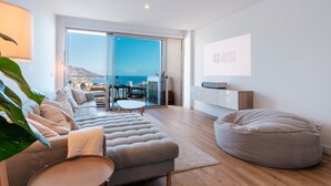Una sala de estar moderna con un sofá, un sillón inflable, un televisor de pantalla plana y un balcón con vistas a la ciudad.