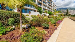 Un hotel moderno con varios balcones, exuberantes jardines y vistas a montañas distantes.