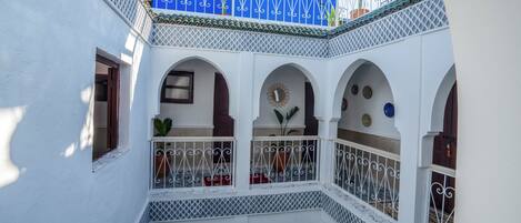 A multi-level courtyard with white walls, blue accents, and decorative metal railings.