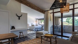 Une chambre moderne dotée d’une grande fenêtre, d’un plafond en bois et d’un coin repas agrémenté d’un tapis tissé.