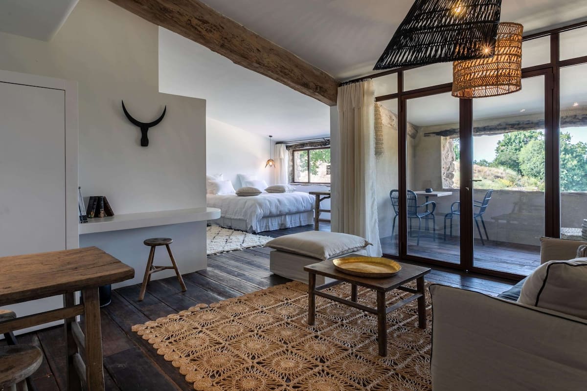 Een moderne slaapkamer met een groot raam, een houten plafond en een eethoek met een geweven vloerkleed.