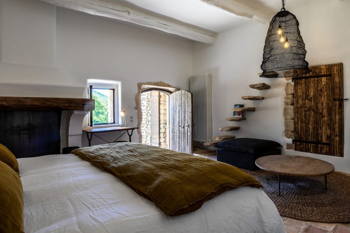 Een slaapkamer met een bed, bureau, hanglamp en een stenen muur.